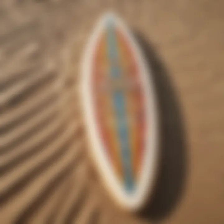 A close-up of a surfboard with vibrant designs lying on the sandy beach.