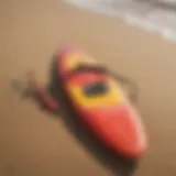 A vibrant surfboard with paddle gear resting on a sandy beach, illustrating the essentials of paddle competition.