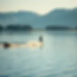 A serene lake with a surfer riding a wake created by a boat, showcasing the beauty of inland surfing.