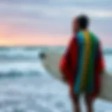 Surfer in a vibrant towelling poncho by the ocean